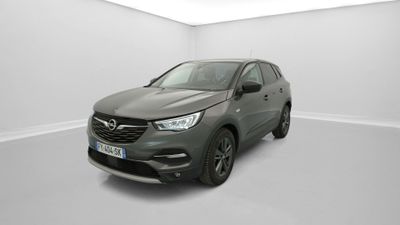 Une voiture grise est garée dans une pièce blanche