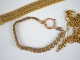 two pieces of gold chains and a bracelet on a white surface