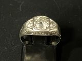 une bague en argent sertie d'un diamant, posée sur une surface noire