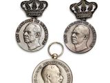 trois médailles d'argent ornées d'une couronne sur fond blanc