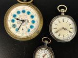 trois montres de poche différentes posées sur une surface noire