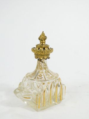 an antique glass perfume bottle with a gold top on a white surface