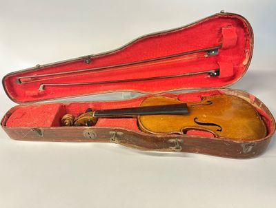 un vieil étui à violon contenant un violon, posé sur une surface blanche