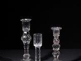 three clear glass candlesticks sitting on a black surface