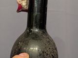 a hand holding a bottle of wine that is sitting on a table