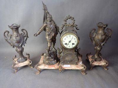 trois statues en bronze et une horloge posée sur une table