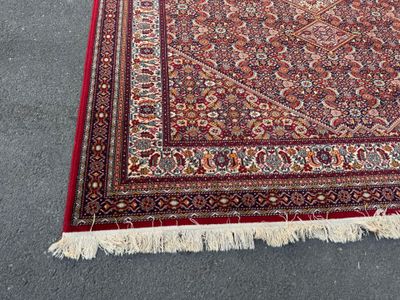 an oriental rug with a red border and fringes on the floor