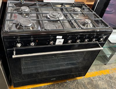 a black stove with four burners and a glass shelf