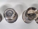three silver cups are lined up on a white surface