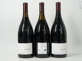 trois bouteilles de vin rouge sont alignées sur une surface blanche