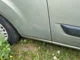 un chat assis dans l'herbe à côté d'une voiture