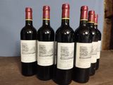 six bottles of red wine are lined up on a table
