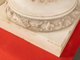 a white marble pedestal with a red table cloth