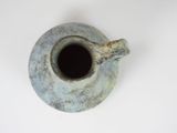 a blue vase with a brown handle on a white surface