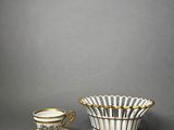 a white and gold cup and saucer with a saucer on the side