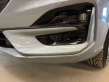 the front end of a white car with a chrome bumper