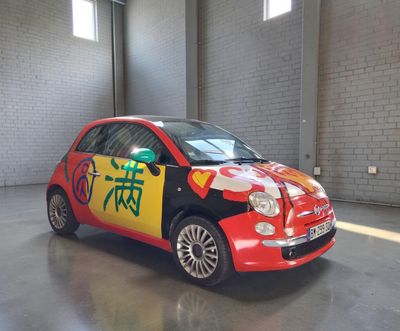 une petite voiture rouge sur laquelle sont peints des caractères chinois