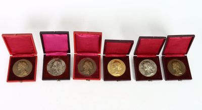 six gold and silver coins in a red box on a white surface