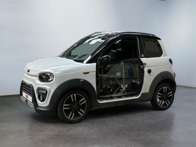 La petite voiture blanche est garée dans la pièce, les portières ouvertes.
