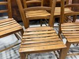 many wooden chairs that are lined up in a room