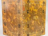 an old book with a golden cover sitting on top of a white surface