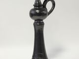 an old black vase sitting on top of a white table