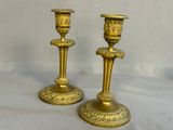 two gold candlesticks sitting on a white table
