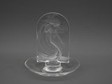 une figurine en verre transparent représentant une femme posée sur un plateau