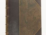 an old book with a brown cover sitting on a white surface