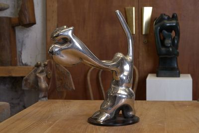 une statue en argent posée sur une table en bois dans une pièce