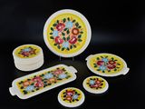 a yellow plate with flowers on it next to a set of coasters and plates