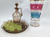 deux tasses et un pichet posés sur un plateau, à côté d’un plateau contenant des verres à shot