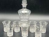 six shot glasses and a decanter sitting on a table