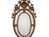 un miroir ovale avec un cadre doré orné de feuilles