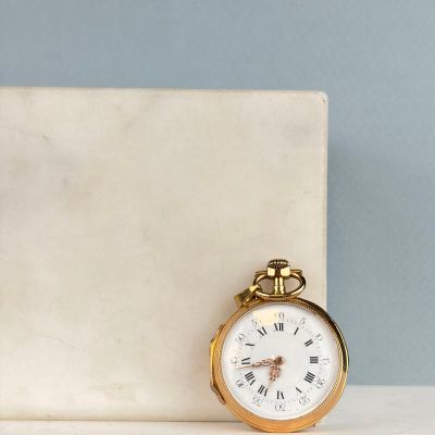 une montre de poche en or posée sur un bloc de marbre