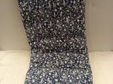 le dos d'un coussin de chaise à motifs floraux bleus et blancs posé sur une surface blanche