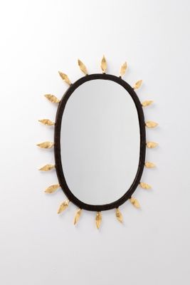 un miroir ovale noir orné de feuilles dorées et doté d'un cadre noir