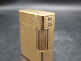 a gold lighter sitting on a table with a black background