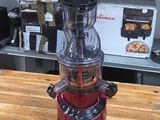 a red juicer sitting on top of a wooden table