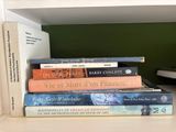 several books are stacked on a shelf in a room