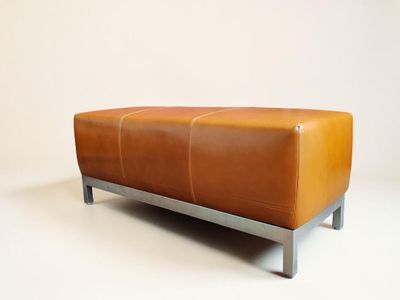 banquette en cuir marron avec des pieds en métal sur fond blanc