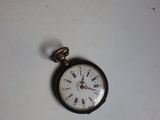 une petite montre de poche posée sur une table blanche