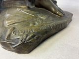 a bronze statue of a woman sitting on a rock
