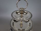 a three tiered silver plate with a ring on top of it