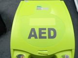 an aed machine sitting on the floor next to a suitcase
