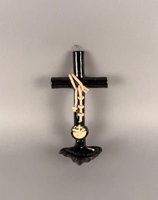une croix noire accrochée au mur, sur laquelle est apposée une croix dorée