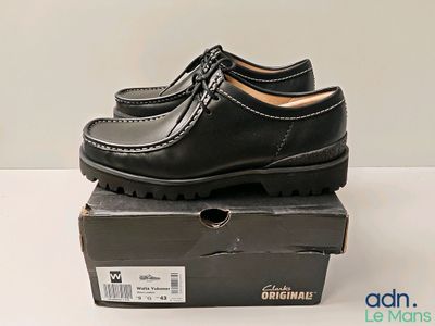men ' s black dress shoes on top of a box on a white surface