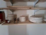 many plates and bowls on the shelves in the kitchen