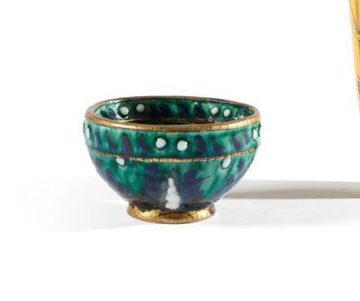 un bol vert et bleu posé à côté d'un vase jaune