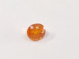 a close up of an orange sapphire stone on a white surface